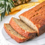 Pineapple Banana Bread on a plate partially sliced.