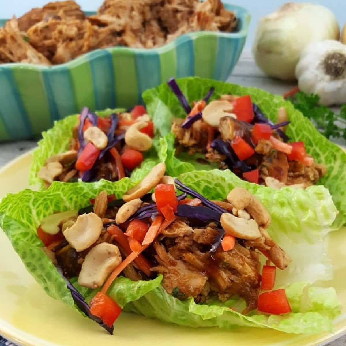 Pulled Pork Lettuce Wraps with peppers, cabbage, and cashews on a plate.