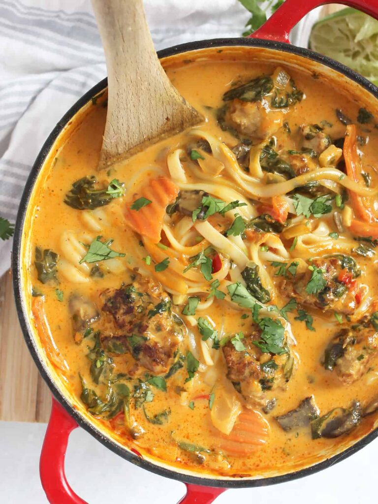 Recipes Using Meatballs: Thai Meatball Soup with Rice Noodles in a pot with a wooden spoon.