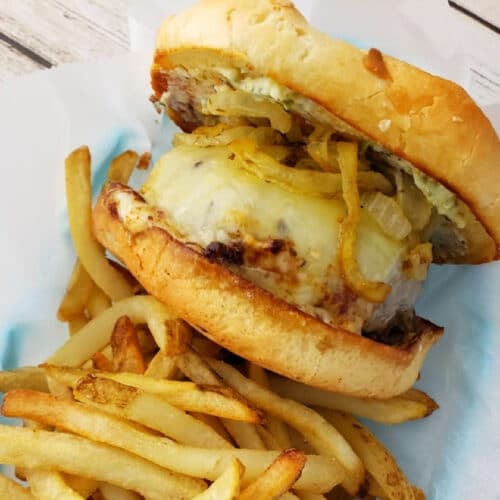Butter Burger with cheese and carmelized onions on a toasted roll with fries.