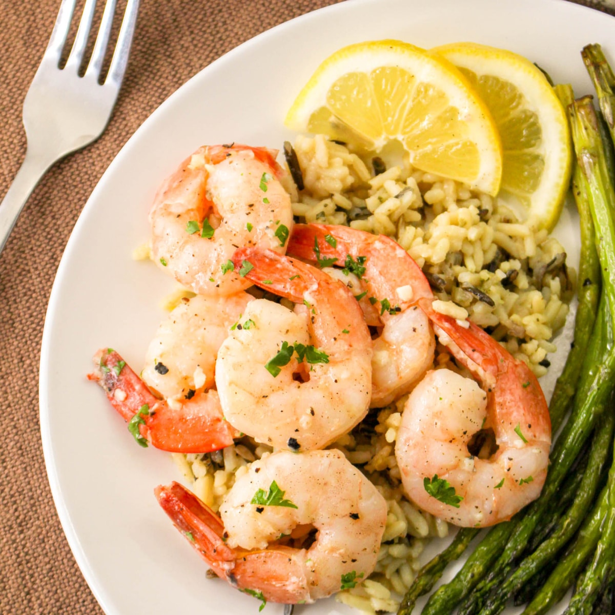 Garlic Butter Shrimp on a plate with lemon, rice, and asparagus.