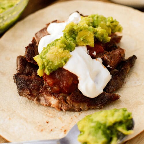 Steak Taco Recipe: steak with salsa, sour cream, and guacamole on a flour tortilla.