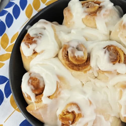 Pumpkin Cinnamon Rolls with cream cheese icing in a baking dish.