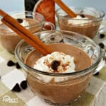 Small cups with Pumpkin Spice Hot Chocolate garnished with ciannmon sticks and whipped cream.