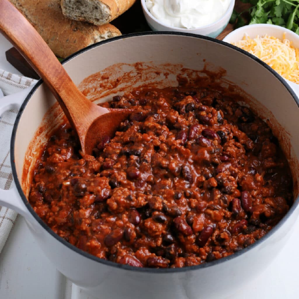 Pot of Chili with a wooden spoon.