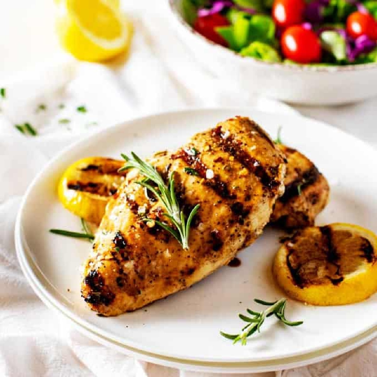 Grilled Lemon Pepper Chicken on a plate with grilled lemons.