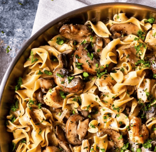 A close-up of a bowl filled with egg noodles and sautéed mushrooms, topped with chopped parsley. This creamy, hearty pasta meal is perfect alongside 30 Minute Chicken Recipes for a quick and satisfying dinner.