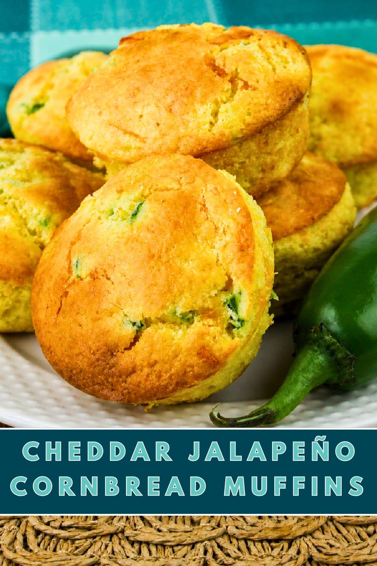 Golden cheddar Jiffy Jalapeno Cornbread Muffins are stacked on a white plate next to a fresh jalapeño pepper. Text at the bottom reads: Cheddar Jalapeño Cornbread Muffins.