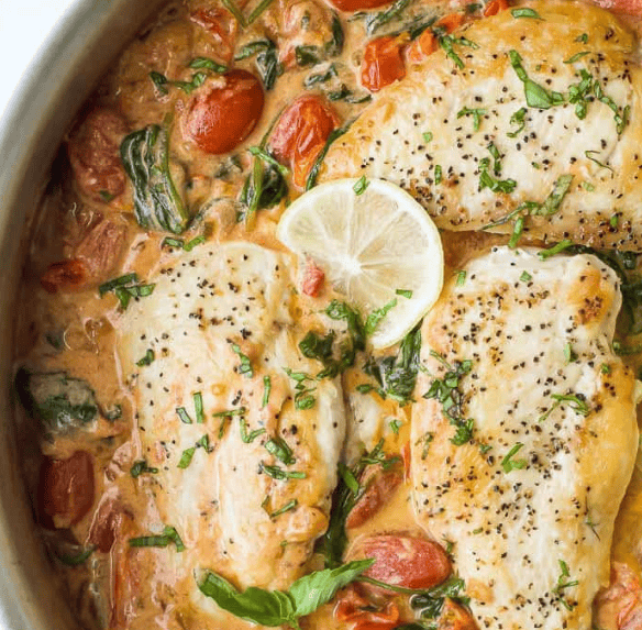 Enjoy this 30 Minute Chicken Recipe: three seasoned chicken breasts simmered in a creamy sauce with cherry tomatoes, spinach, fresh herbs, and a slice of lemon—all cooked together in one skillet.