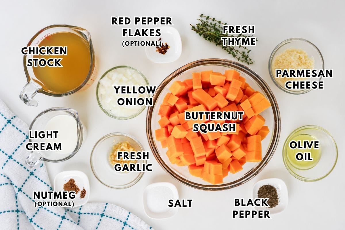 Top-down view of labeled butternut squash soup ingredients in bowls, including squash, onion, garlic, chicken stock, cream, nutmeg, thyme, red pepper flakes, parmesan, olive oil, salt, and pepper.